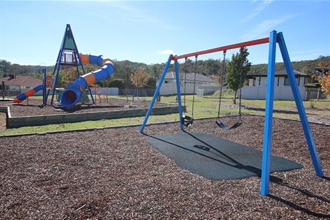 Gracelands park showing two swings and large climbing frame with covered slide