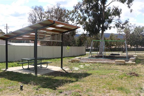 Hayley Park East showing covered seating and swings